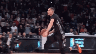 A Basketball Player Is Dribbling A Ball On A Court In Front Of A Verizon Sign . GIF