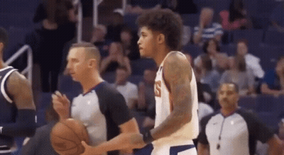 A Basketball Player Is Dribbling A Basketball While A Referee Looks On . GIF