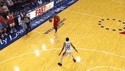 A Basketball Player Is Dribbling The Ball On A Court While Another Player Tries To Block Him . GIF