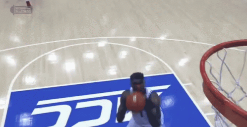 A Basketball Player Is Dunking A Ball On A Court With A Sign That Says Ucsd GIF