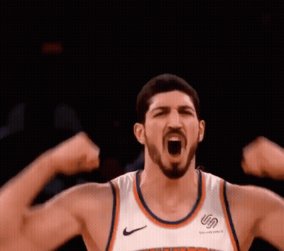 A Basketball Player Is Flexing His Muscles While Wearing A New York Knicks Jersey . GIF