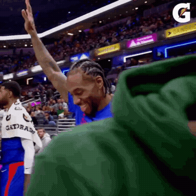 A Basketball Player Is Giving A High Five To The Crowd While Wearing A Green Gatorade Shirt . GIF