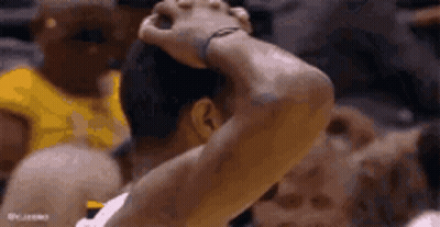 A Basketball Player Is Holding His Head In His Hands While Playing A Game . GIF