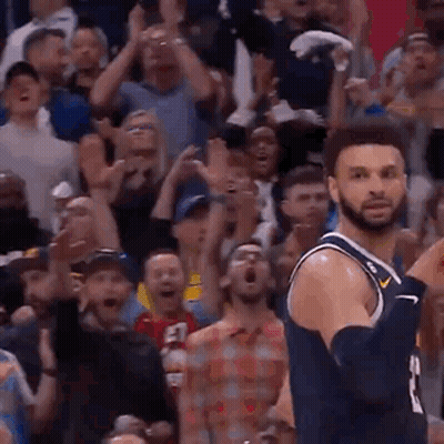 A Basketball Player Is Jumping In The Air In Front Of A Crowd Of People . GIF