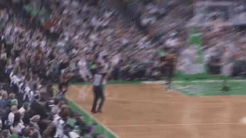 A Basketball Player Is Jumping In The Air In Front Of A Crowd Of People On A Court . GIF