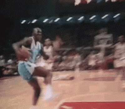 A Basketball Player Is Jumping In The Air While Holding A Basketball In His Hand . GIF