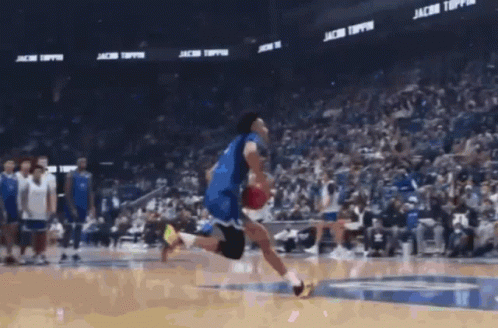 A Basketball Player Is Jumping In The Air With A Ball In Front Of A Banner That Says Jacob Toppin GIF