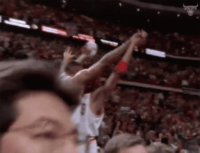 A Basketball Player Is Jumping In The Air With His Arms In The Air While A Crowd Watches . GIF