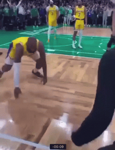 A Basketball Player Is Kneeling On The Floor During A Game While A Referee Watches . GIF