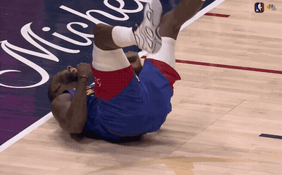 A Basketball Player Is Laying On His Back On A Court With Michigan Written On It GIF