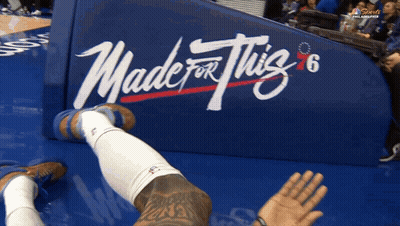 A Basketball Player Is Laying On The Floor In Front Of A Banner That Says Made For This GIF