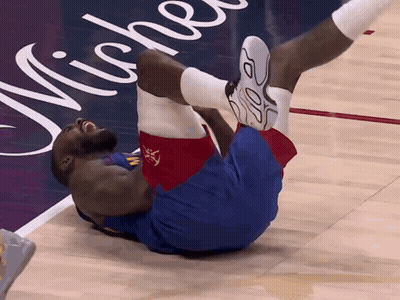 A Basketball Player Is Laying On The Floor With His Knee In Pain GIF