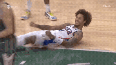 A Basketball Player Is Laying On The Floor With His Legs Crossed And Smiling . GIF
