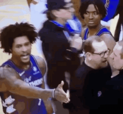 A Basketball Player Is Shaking Hands With A Referee While Standing Next To A Group Of Men . GIF
