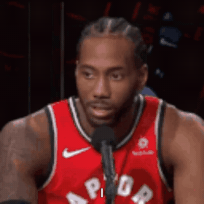 A Basketball Player Is Sitting In Front Of A Microphone . GIF