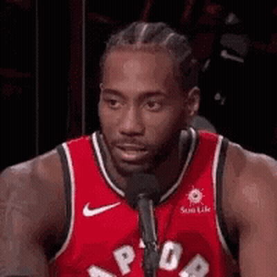 A Basketball Player Is Sitting In Front Of A Microphone . GIF