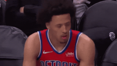 A Basketball Player Is Sitting In The Stands During A Game Wearing A Red Jersey With The Word Detroit On It . GIF