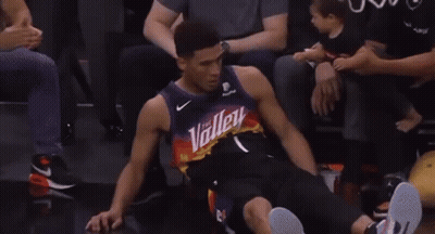 A Basketball Player Is Sitting In The Stands Giving A Thumbs Up To His Fans . GIF