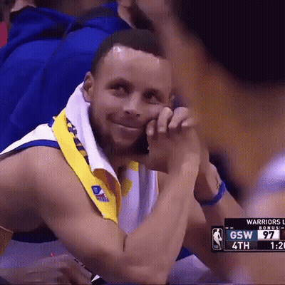 A Basketball Player Is Sitting In The Stands With A Towel Around His Neck And Smiling . GIF