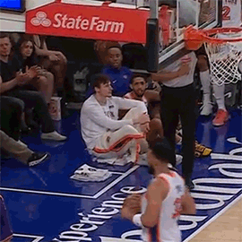 A Basketball Player Is Sitting On The Floor During A Game While A Referee Looks On . GIF