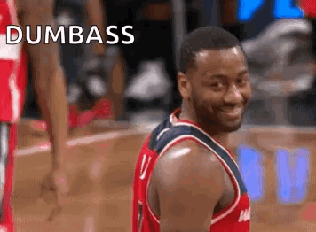 A Basketball Player Is Smiling And Looking At The Camera While Standing On A Basketball Court . GIF