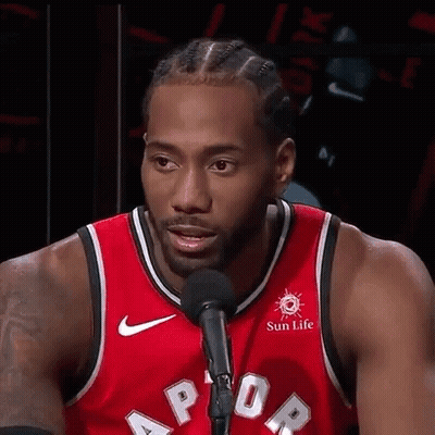 A Basketball Player Is Standing In Front Of A Microphone And Talking Into It . GIF