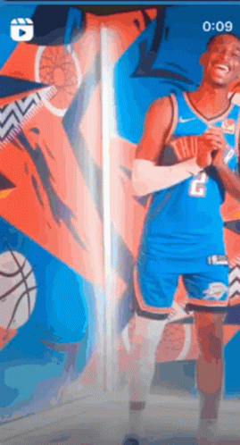 A Basketball Player Is Standing In Front Of A Wall With A Basketball In The Background . GIF