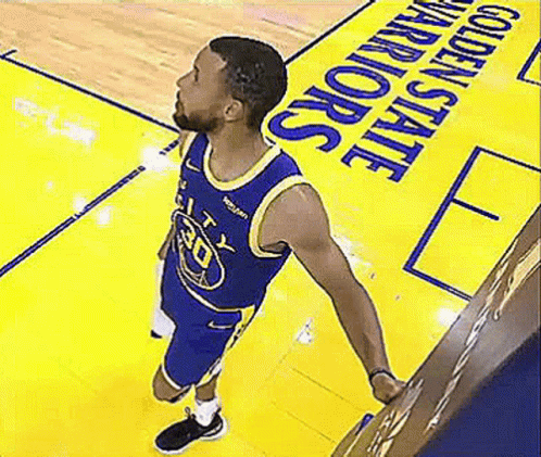 A Basketball Player Is Standing On A Basketball Court In Front Of A Golden State Warriors Sign . GIF