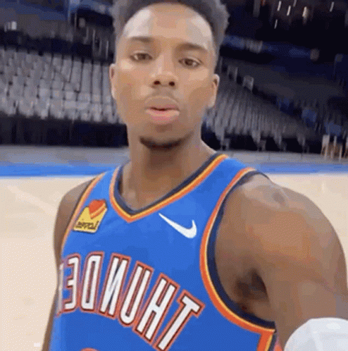 A Basketball Player Is Taking A Selfie On A Basketball Court While Wearing A Blue Jersey . GIF