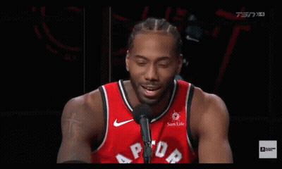 A Basketball Player Is Talking Into A Microphone While Wearing A Red Raptors Jersey . GIF