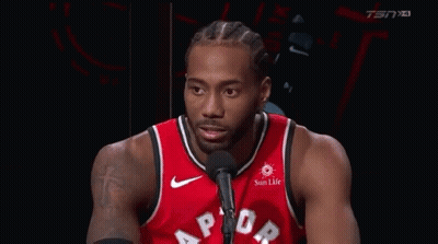 a basketball player is talking into a microphone while wearing a red raptors jersey .