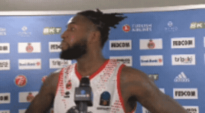 A Basketball Player Stands In Front Of A Blue Wall With Turkish Airlines And Fedecom Logos On It GIF