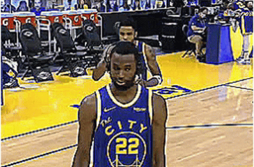 A Basketball Player Wearing A Blue Jersey With The Number 22 On It Is Walking On The Court . GIF