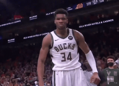 A Basketball Player Wearing A Bucks 34 Jersey Stands In Front Of A Crowd GIF