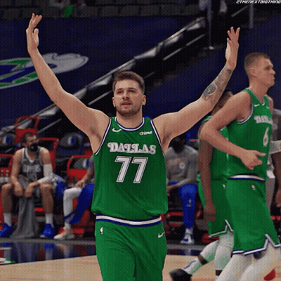 A Basketball Player Wearing A Dallas 77 Jersey Is Raising His Arms In The Air GIF