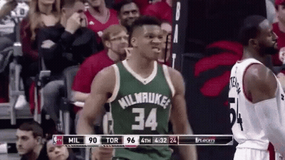 A Basketball Player Wearing A Green Jersey With The Number 34 On It Is Standing In Front Of A Crowd Of People . GIF