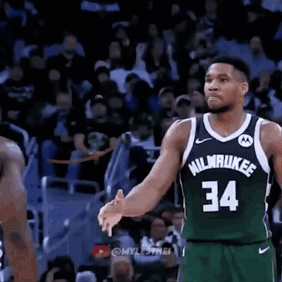 A Basketball Player Wearing A Green Jersey With The Number 34 On It Is Talking To Another Player On The Court . GIF