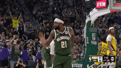 A Basketball Player Wearing A Green Milwaukee Jersey Stands In Front Of A Crowd GIF