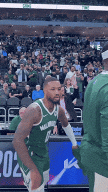 A Basketball Player Wearing A Green Milwaukee Jersey Stands On The Court GIF