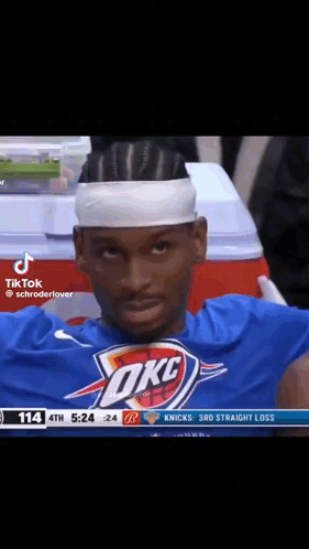 A Basketball Player Wearing A Headband And A Okc Shirt Is Sitting In The Stands During A Game . GIF