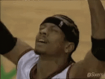 A Basketball Player Wearing A Headband Is Raising His Arms In The Air . GIF