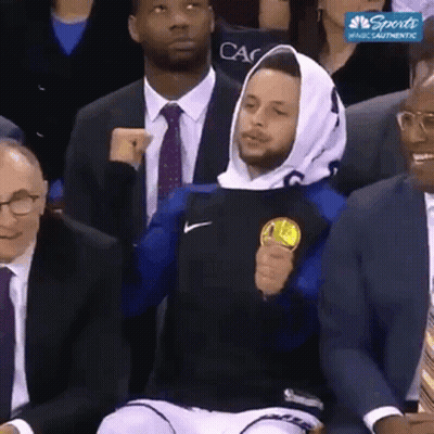 A Basketball Player Wearing A Hoodie Is Sitting In The Stands Holding A Coin . GIF