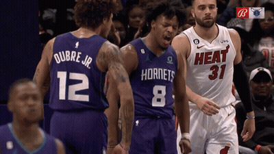 A Basketball Player Wearing A Hornets Jersey Stands Next To A Player Wearing A Heat Jersey GIF