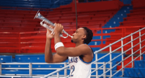 A Basketball Player Wearing A Kansas Jersey Is Blowing A Trumpet GIF