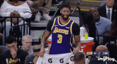 A Basketball Player Wearing A Lakers Jersey Is Holding A White Gatorade Shirt GIF