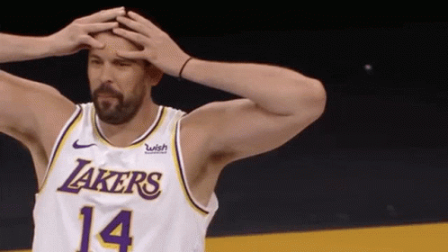 A Basketball Player Wearing A Lakers Jersey Is Holding His Head In His Hands . GIF