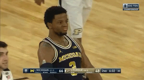A Basketball Player Wearing A Michigan Jersey Stands On The Court During A Game GIF