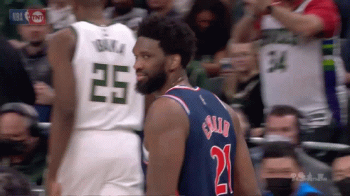 A Basketball Player Wearing A Number 21 Jersey Stands Next To Another Player Wearing A Number 25 Jersey GIF