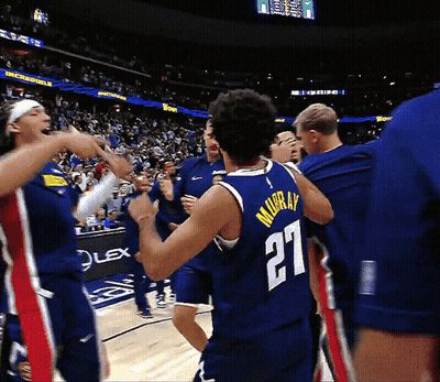 A Basketball Player Wearing A Number 27 Jersey Is Surrounded By His Teammates GIF