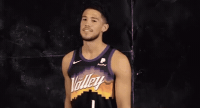 A Basketball Player Wearing A Purple And Black Jersey Is Smiling . GIF
